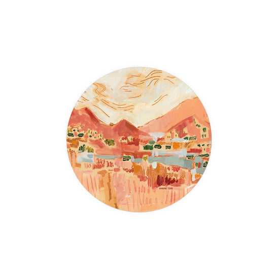 Decorative circular coaster by Margaret Teane with an abstract painting of a mountain landscape.