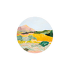 Round landscape art coaster by Margaret Teake, featuring yellow fields, a mountain, and stylized trees.
