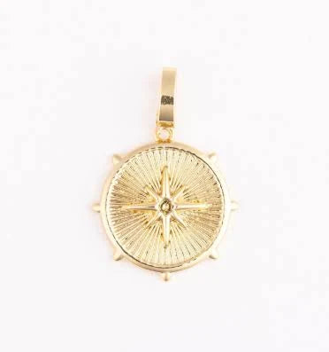 Gold coin charm from Sophie featuring a compass rose design.
