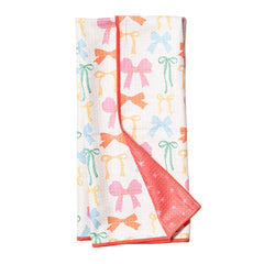 Reversible towel with a bow pattern by August Morgan, showing a bright pink star pattern on the reverse.
